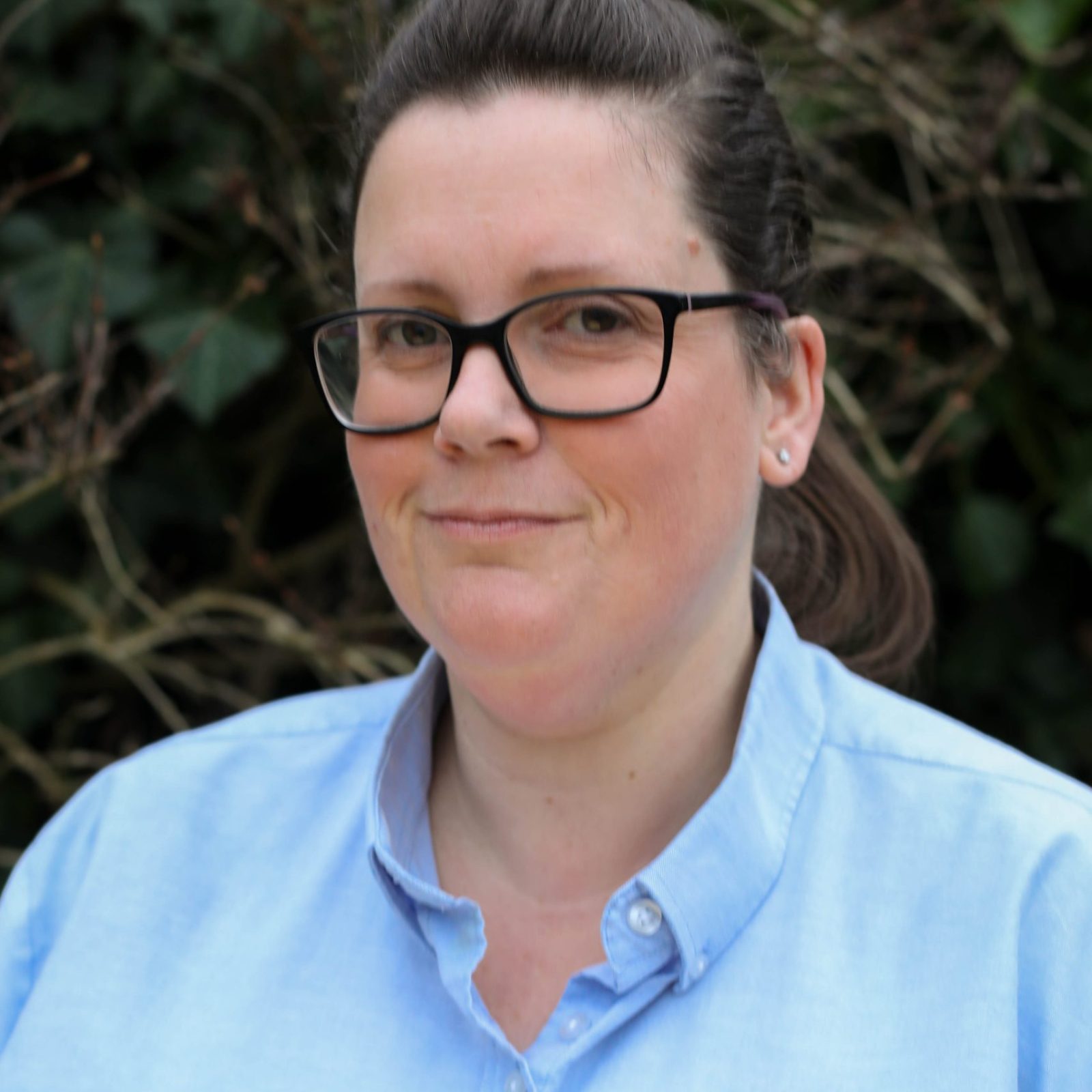 Acorns Nurseries A person wearing glasses and a light blue 
