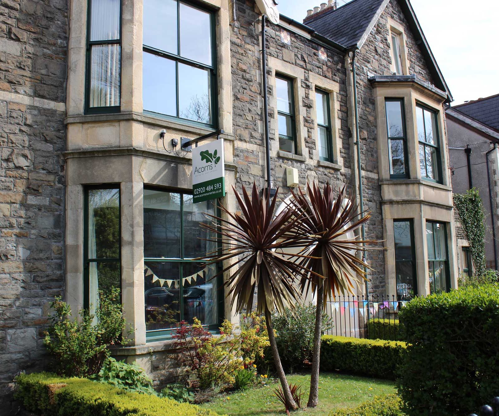 Acorns Nurseries The stone row houses on Oakfield Street feature large windows and a small garden with a spiky plant in front. A sign proudly displaying "Acorns" is visible.