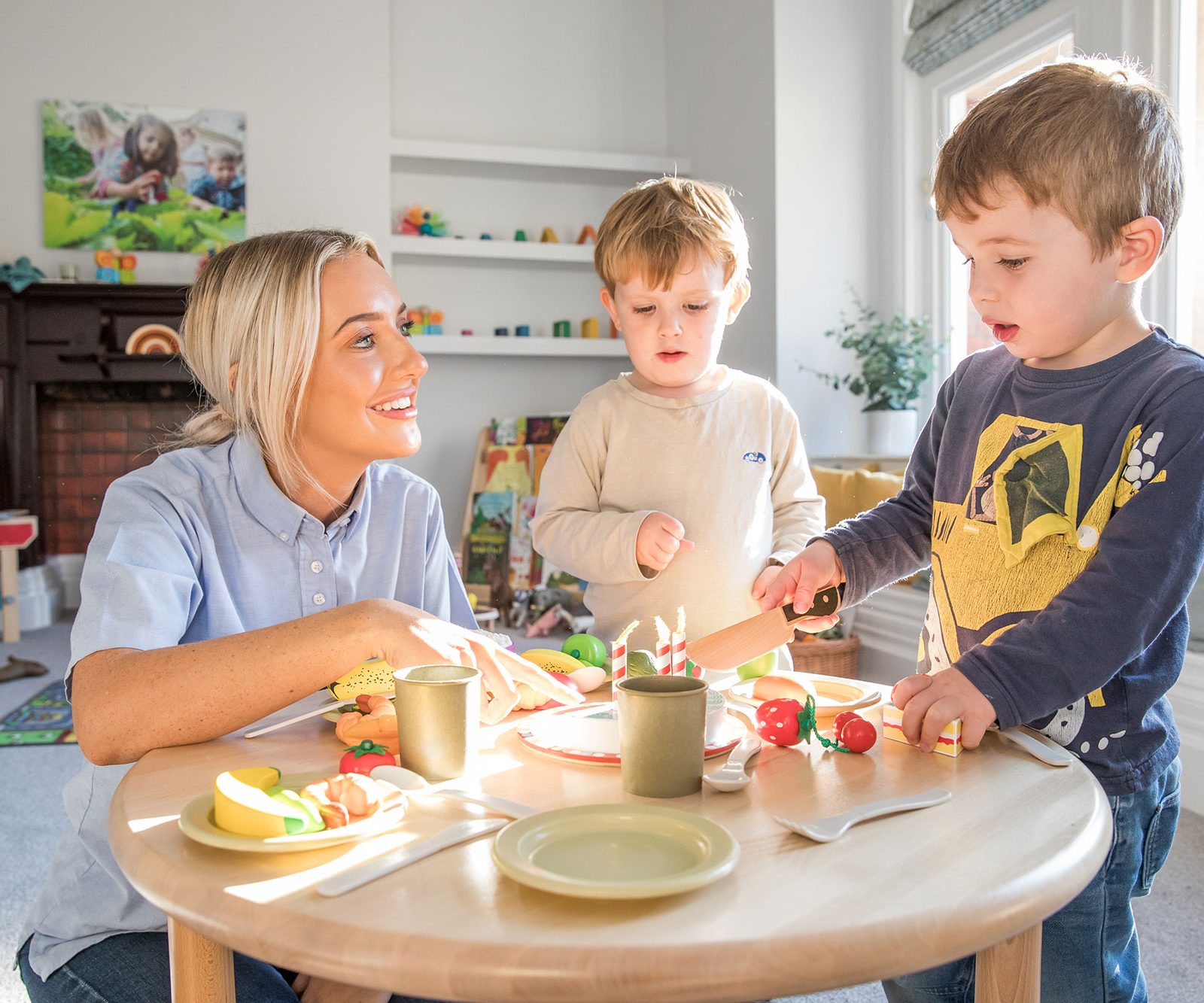 Acorns Nurseries In a bright room in Llandaff, a woman and two children joyfully play with toy food at a small table, their laughter as abundant as acorns scattered on a forest floor.