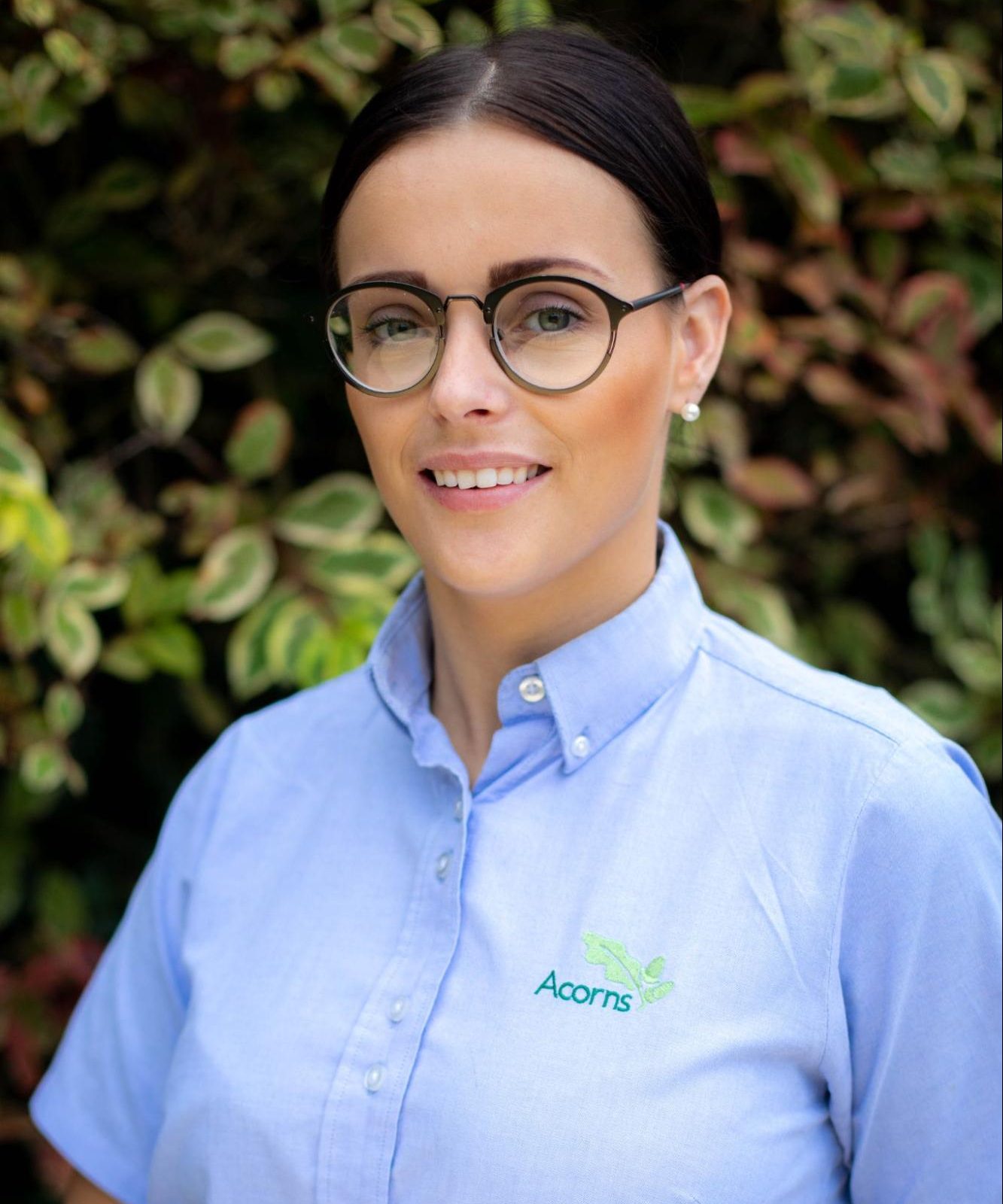 Acorns Nurseries A person wearing glasses and a blue shirt emblazoned with the 